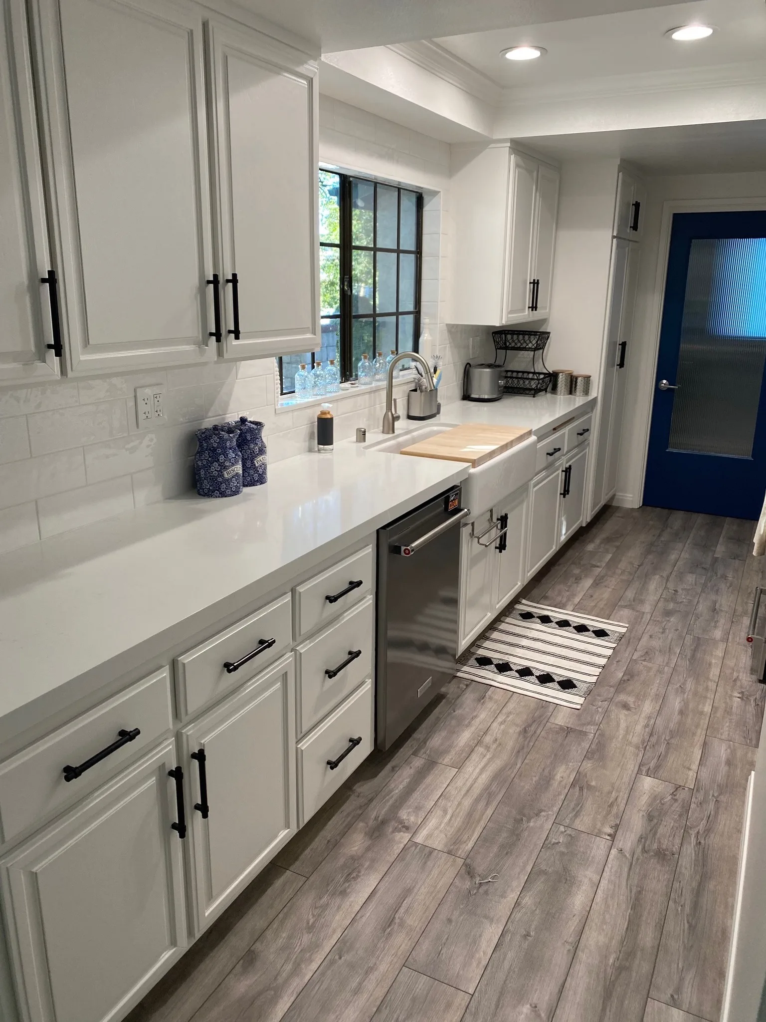 Galley kitchen with light refinished cabinets and black hardware