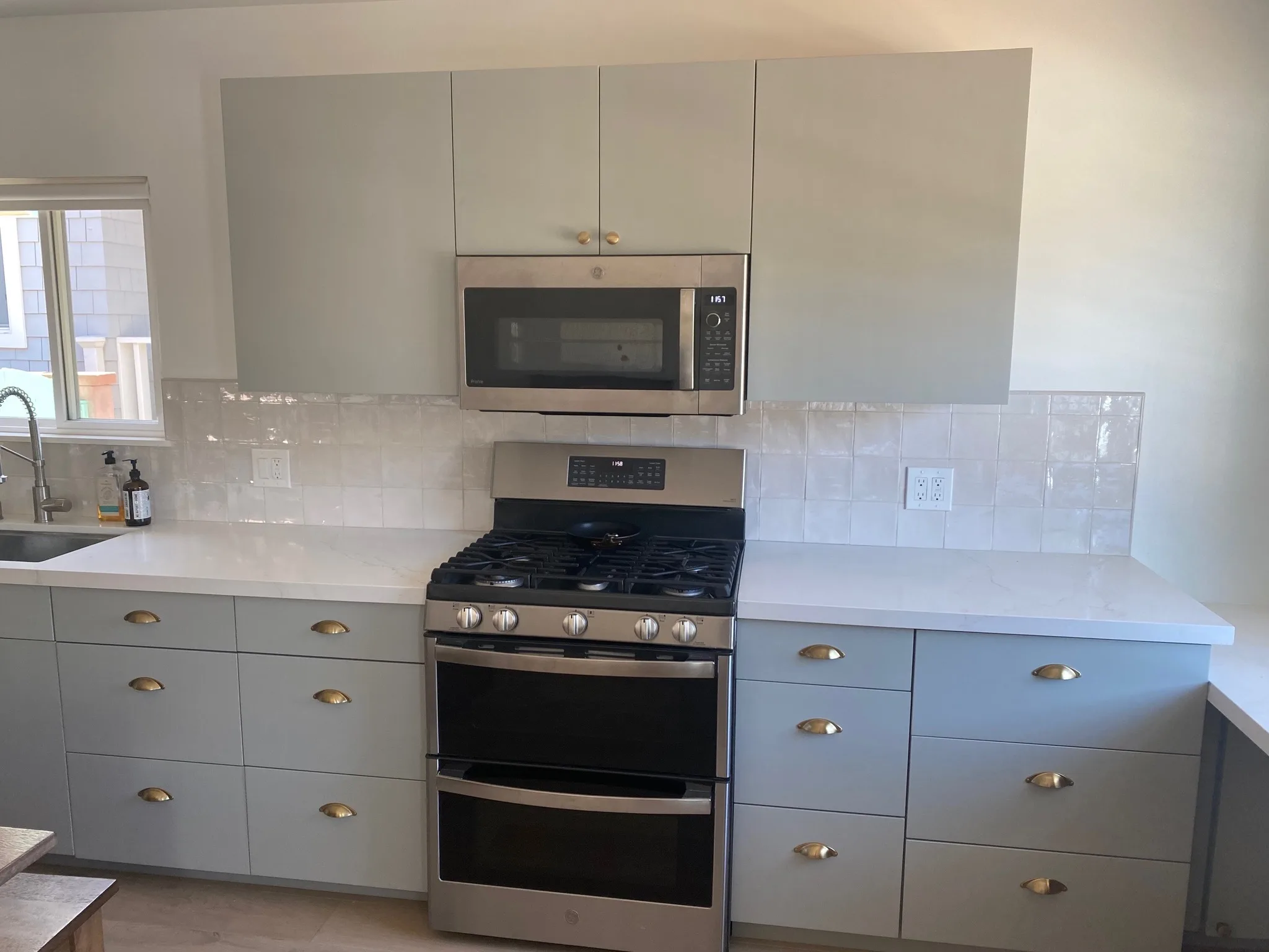Gray refinished cabinets with brass hardware and a double oven