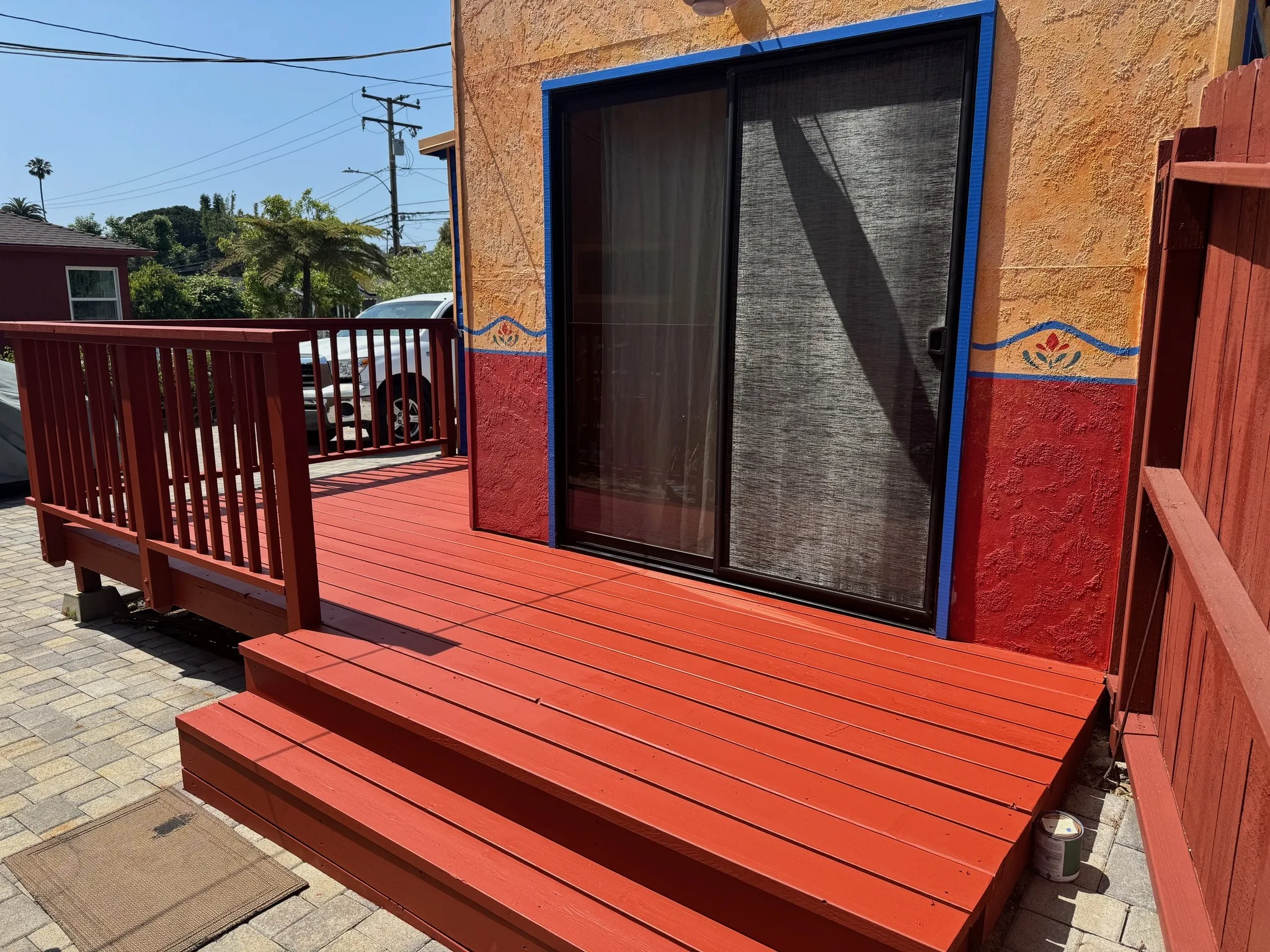 Deck refinished in red-orange beside blue siding