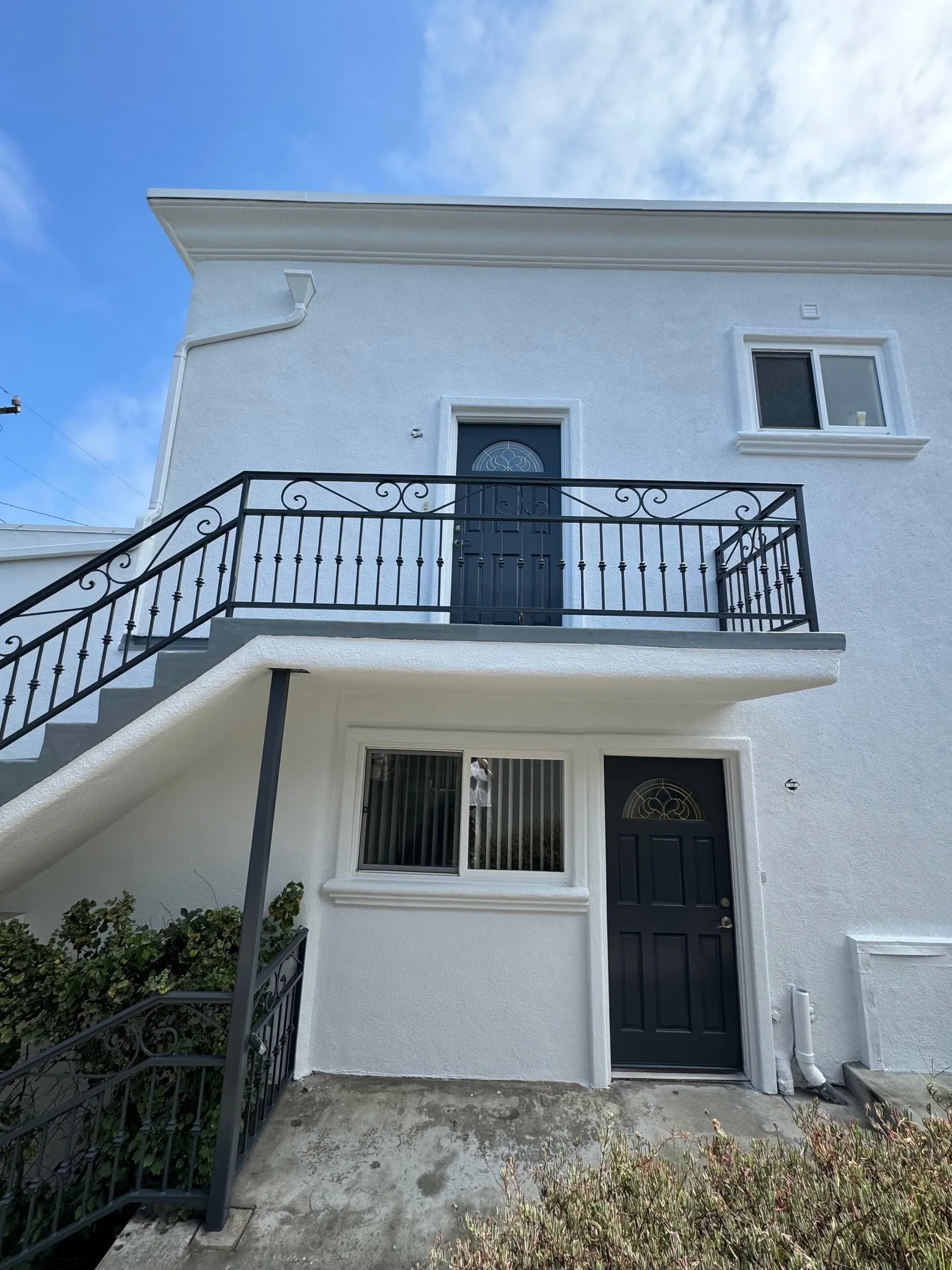 White two-story home with freshly painted balcony railings