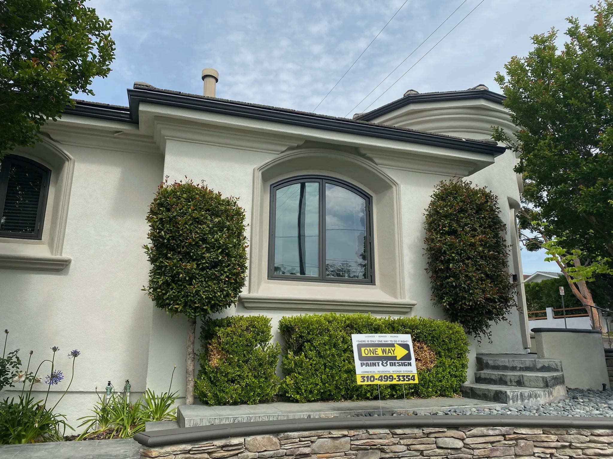White stucco home with arched window and One Way yard sign