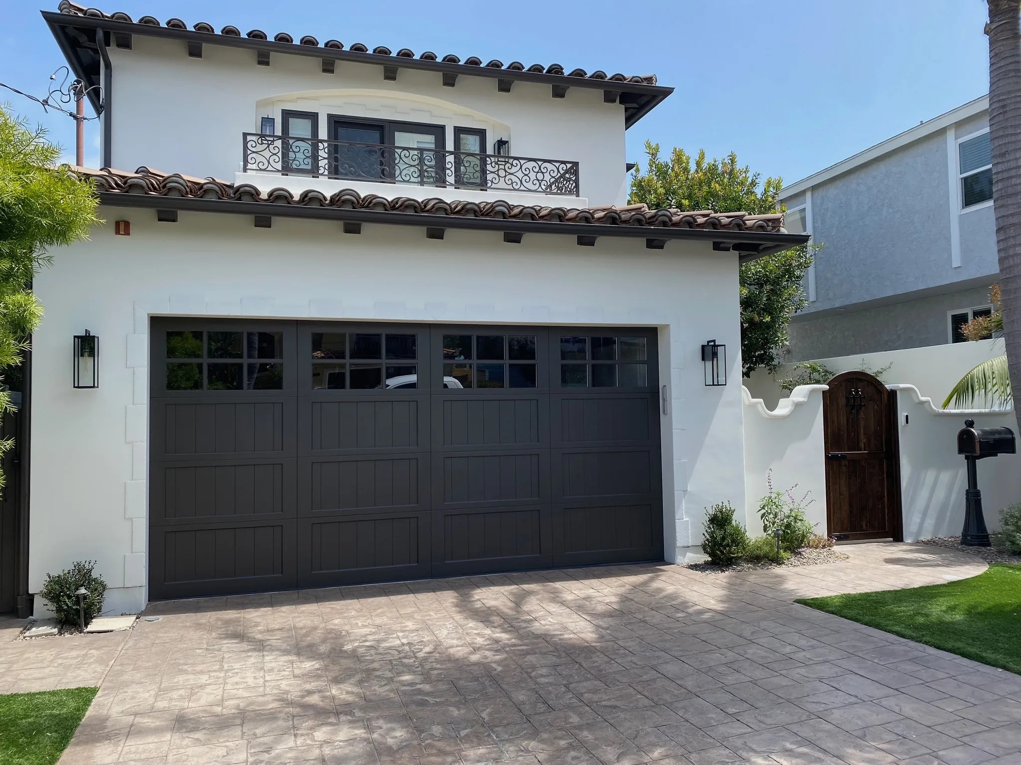 Spanish-style two-story home with freshly painted white exterior and dark garage door