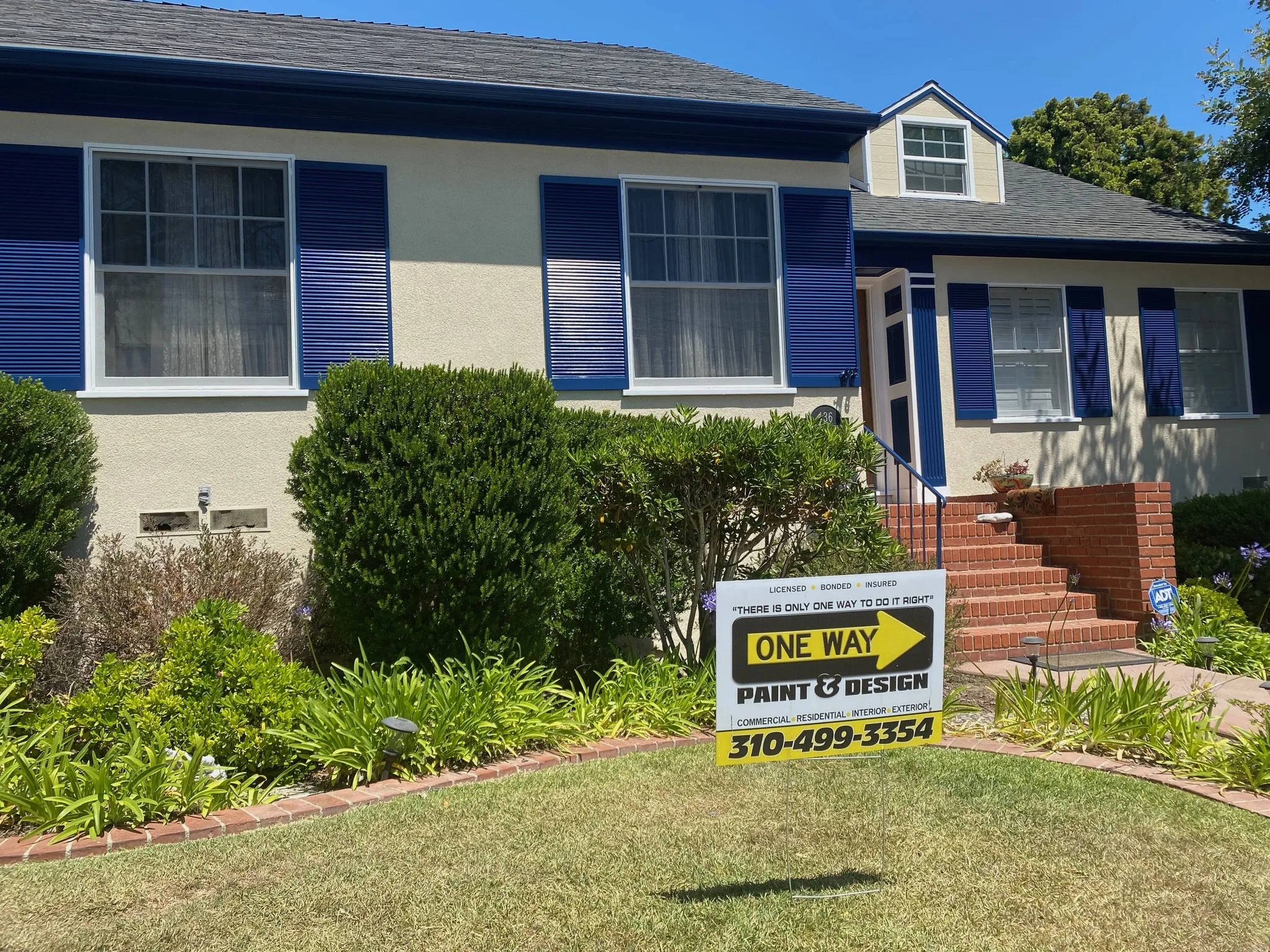 Freshly painted El Segundo cottage with blue shutters and a One Way Paint & Design yard sign