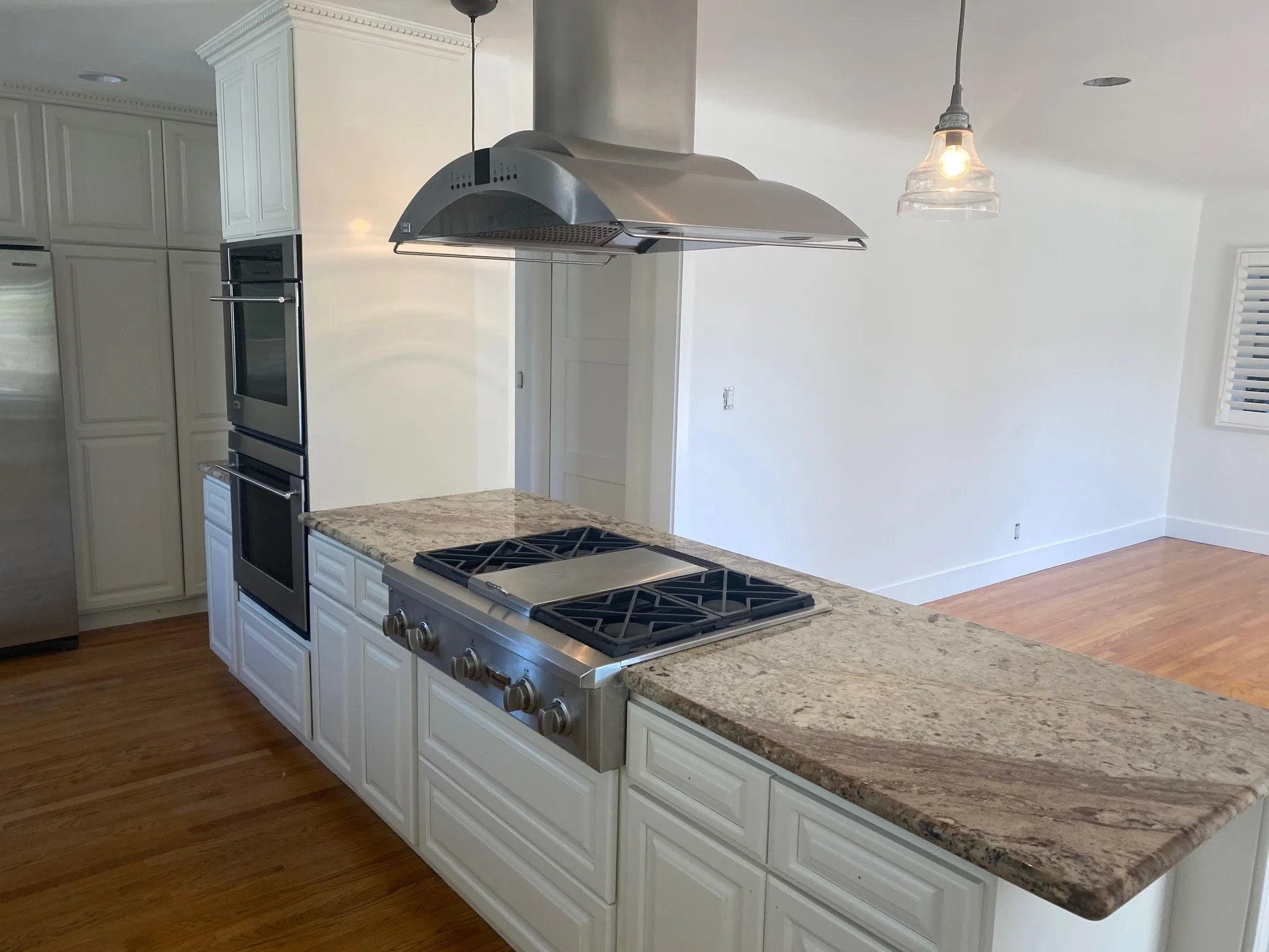 Repainted kitchen with white cabinets, island, and range hood