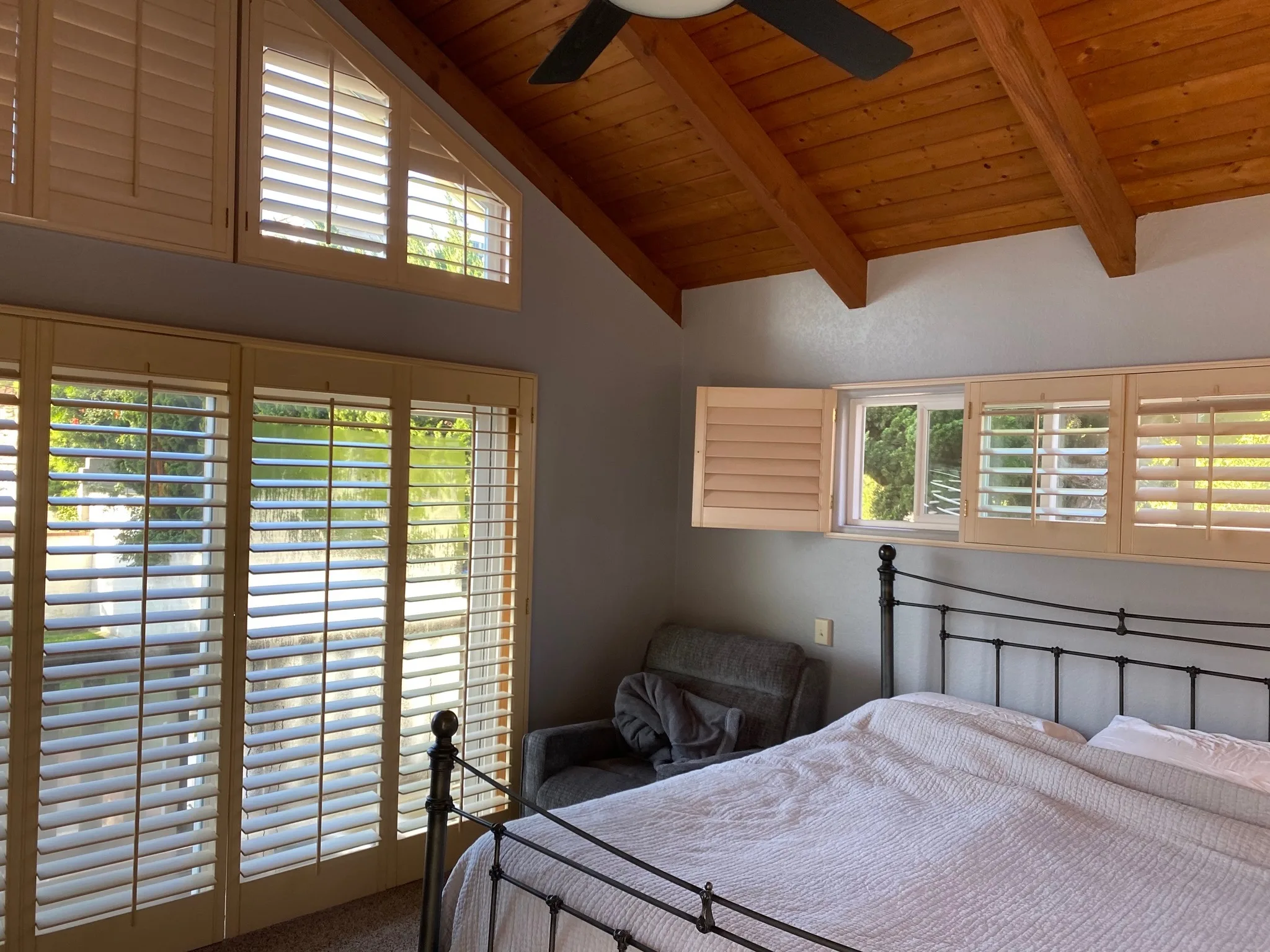 Bedroom with warm wood ceiling, plantation shutters, and freshly painted walls